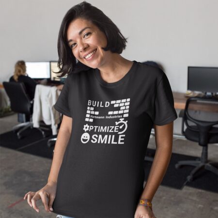 Girl in office environment smiling wearing "Build, Optimize, Smile" T-Shirt
